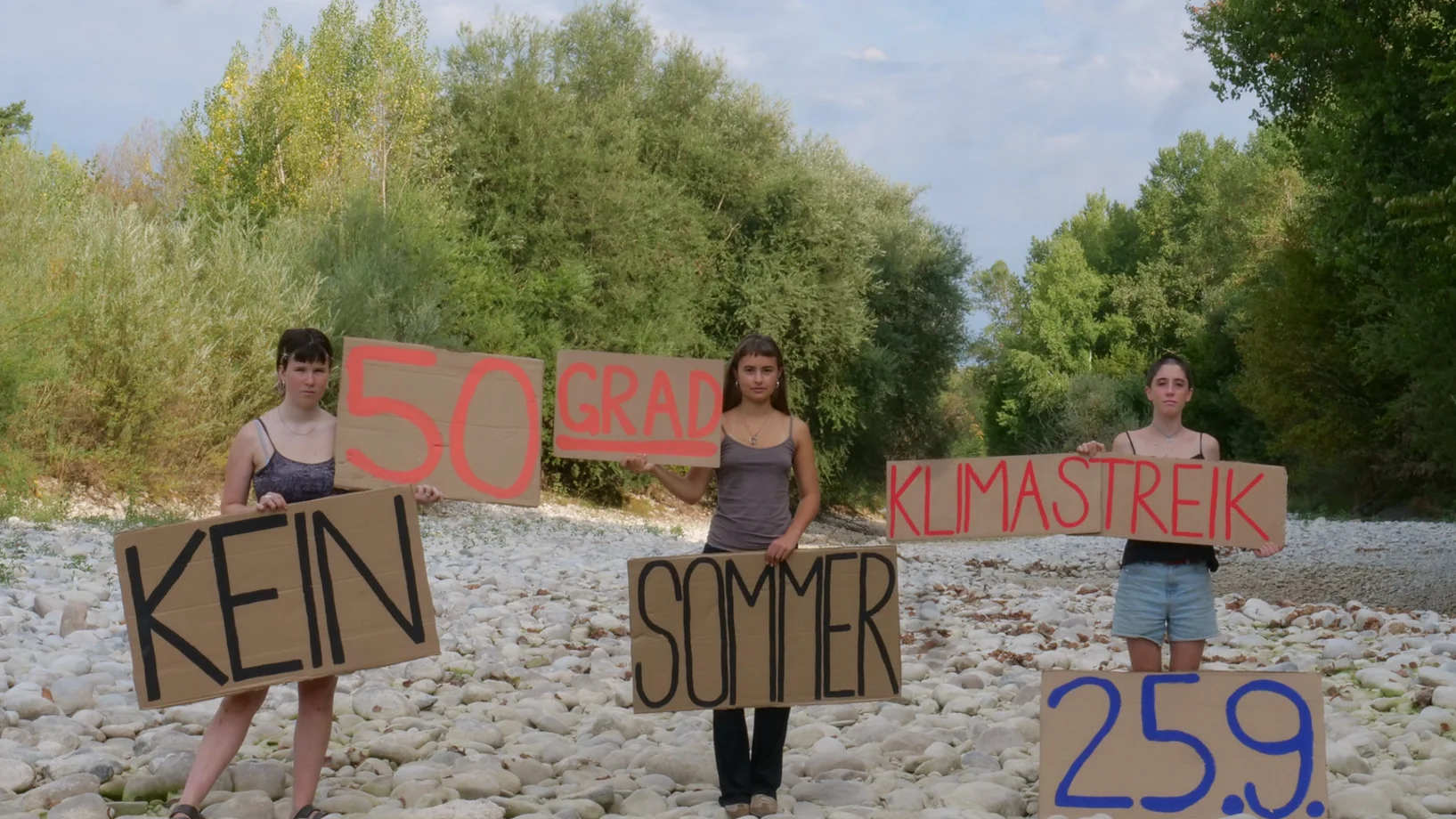Menschen stehen in ausgetrocknetem Bachbett und protestieren für mehr Klimaschutz
